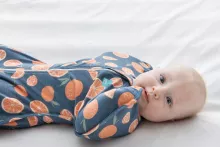 baby in orange swaddle laying down